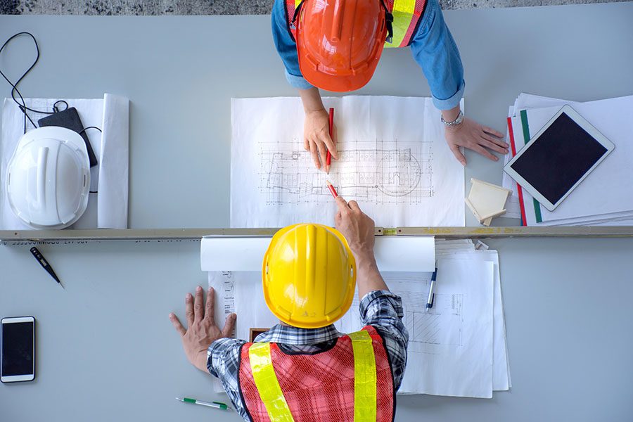 Specialized Business Insurance - Two Contractors Examining New Building Blueprints in the Office
